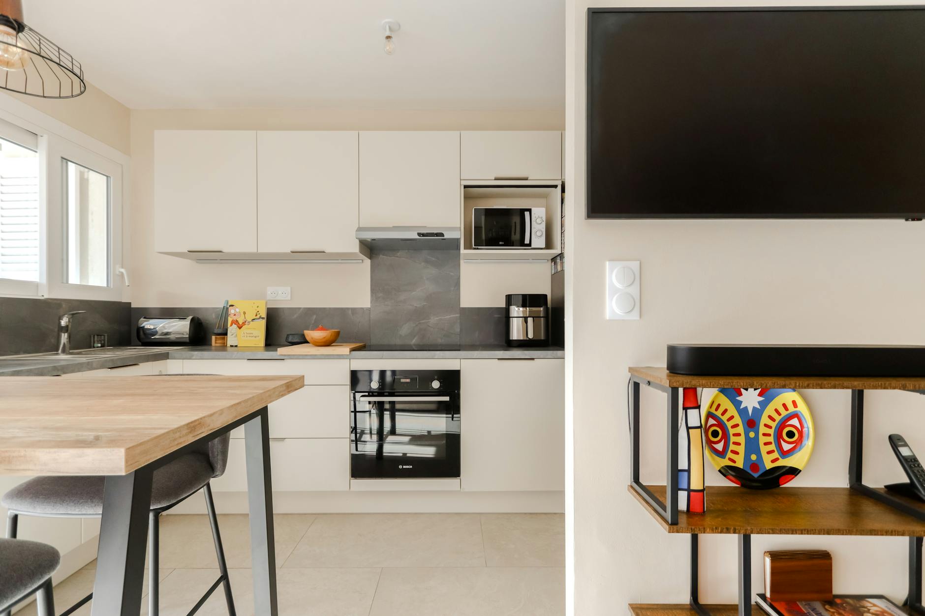 Jasna nowoczesna kuchnia w bloku z gładkimi frontami i dekoracyjnym talerzem