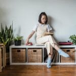 Kobieta czytająca książkę w salonie z roślinami i podłogą w jodełkę