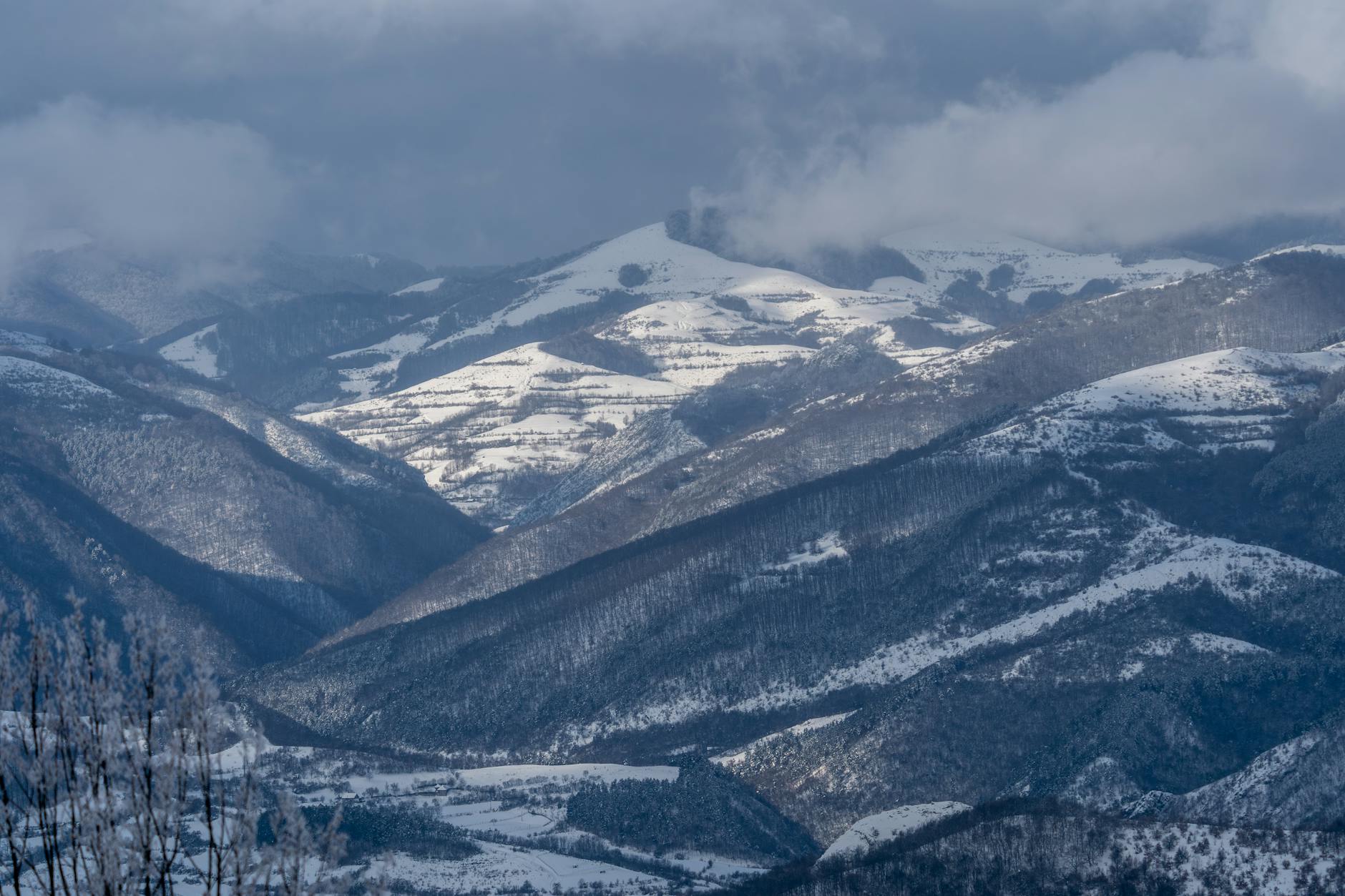Ośnieżone pasmo górskie pod zimowym, pochmurnym niebem