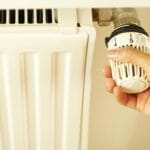 Ręka regulująca termostat grzejnika w domowej instalacji CO