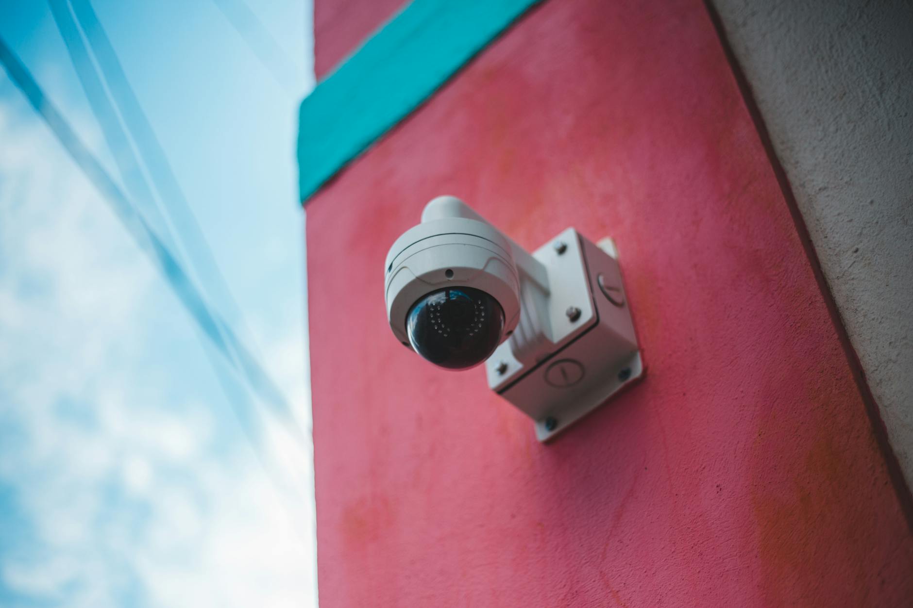 Kamera monitoringu na zewnętrznej ścianie w różowo-turkusowych kolorach