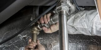 Próba ciśnieniowa instalacji wodnej: jakie ciśnienie zastosować i jak długo testować Zbliżenie dłoni hydraulika montującego stalowe rury wewnątrz budynku
